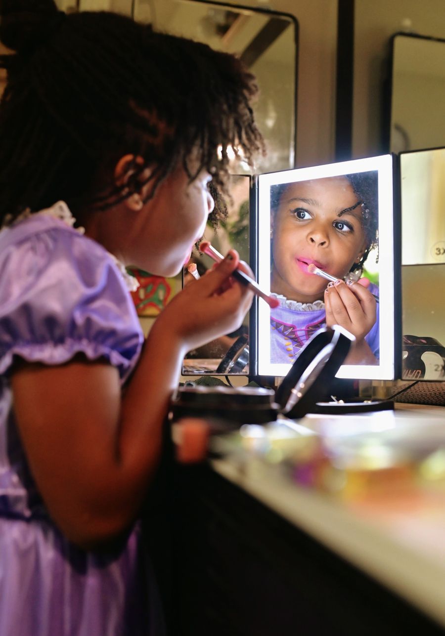 Girl applying lipstick in a lit mirror